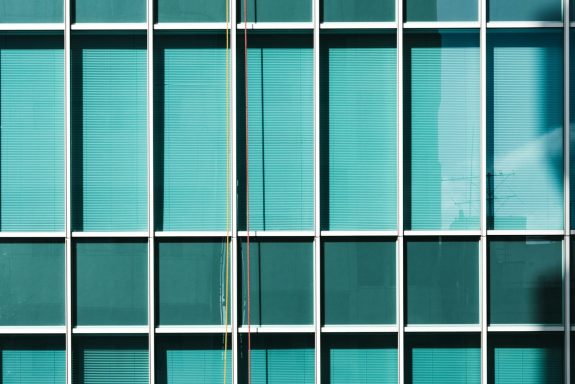 Blaue Fenster mit vertikalen Jalousien in einem modernen Gebäudefassadenmuster.