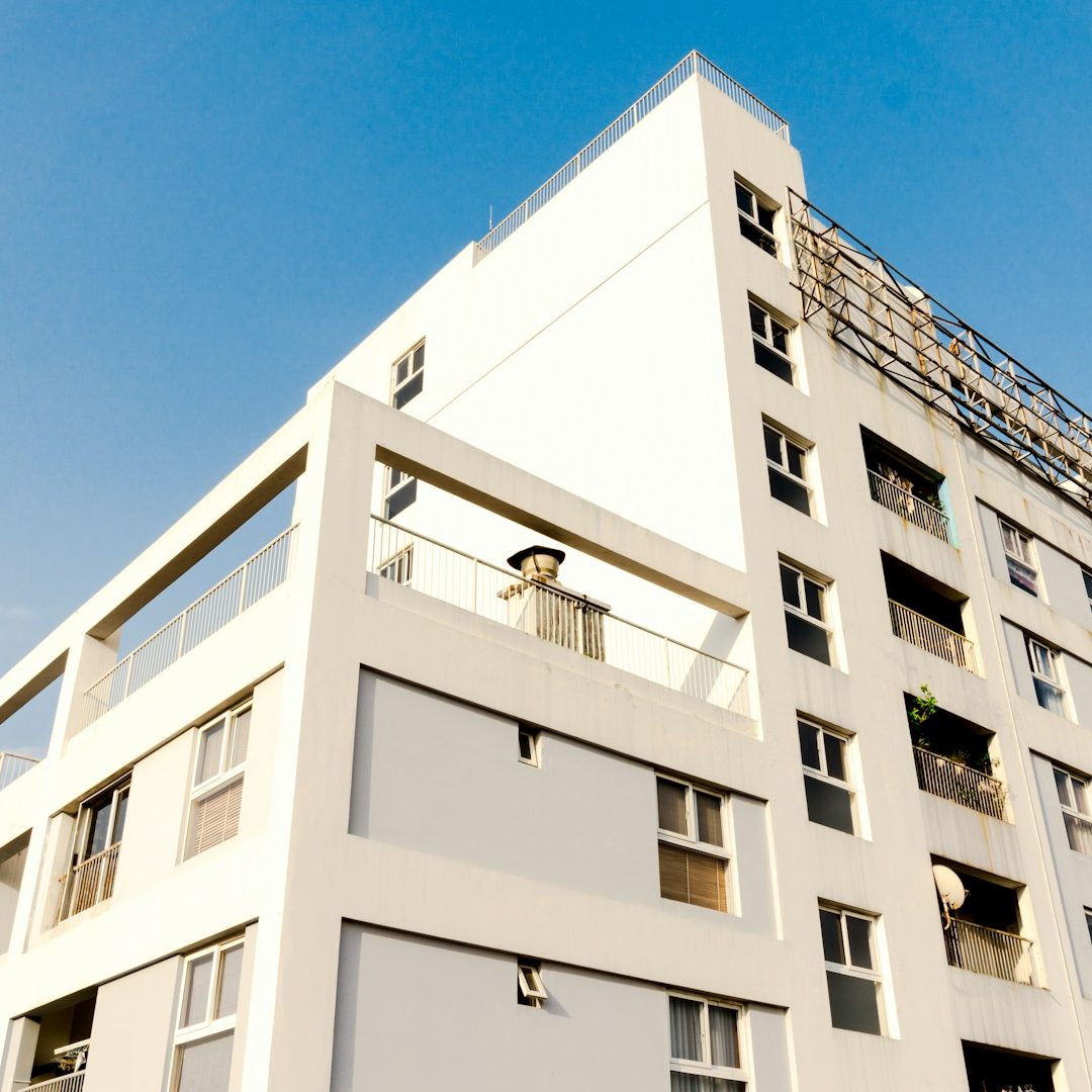 Moderne Wohngebäude mit Balkon und klarer, blauer Himmel im Hintergrund.
