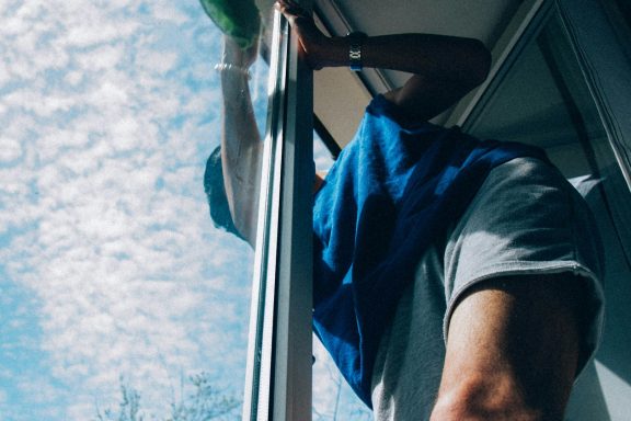 Eine Person reinigt ein Fenster, während der Himmel mit Wolken bedeckt ist.